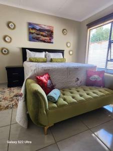 1 dormitorio con sofá verde y cama en Intsingizi bird lodge, en Pretoria