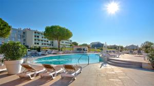 a swimming pool with lounge chairs next to a building at Park Plaza Belvedere Medulin in Medulin