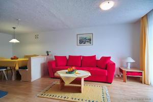 uma sala de estar com um sofá vermelho e uma mesa em Ferienwohnung Bergfeuer im Ferienhaus Weber em Füssen