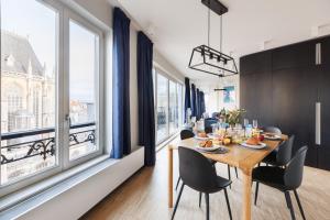 - une salle à manger avec une table, des chaises et de grandes fenêtres dans l'établissement Sweet Inn - Regence, à Bruxelles