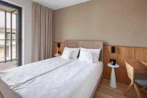 a bedroom with a large white bed with a chair at Apartamenty na Półwyspie Wydma&Las in Jastarnia +257 photos
