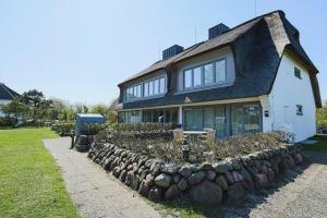 a house with a stone wall in front of it at Wattkoje-Ein-Appartement-der-besonderen-Art-erwartet-Sie-am-Rande-der-Braderuper-Heide in Braderup