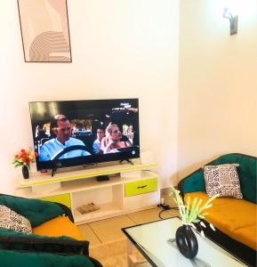 uma sala de estar com uma televisão de ecrã plano em Village des Aviateurs 