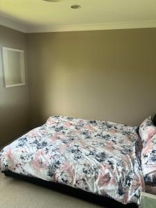 1 dormitorio con 1 cama con edredón de flores en Luxurious and spacious home in taree, en Taree