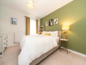 1 dormitorio con cama blanca y pared verde en Pass the Keys Stunning and Stylish Flat Mins From Central London, en Londres