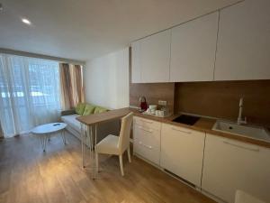 a kitchen with white cabinets and a table and a couch at Festa Chamkoria Apartments in Borovets