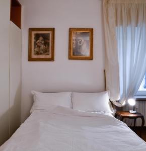 - une chambre avec un lit blanc et deux photos sur le mur dans l'établissement Emily Luxury Apartment, à Vérone