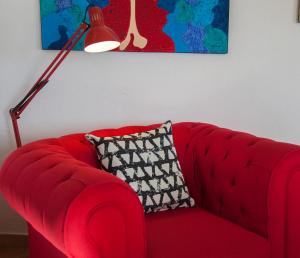 um sofá vermelho com uma almofada e um candeeiro em Villa Bricco Astiani em Montegrosso dʼAsti