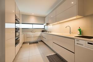 a kitchen with white cabinets and a sink at Seafront Condo at The Pier 25 in Swakopmund +16 photos