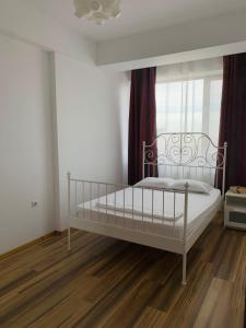 a white bed in a room with a window at The View Apartment in Constanţa