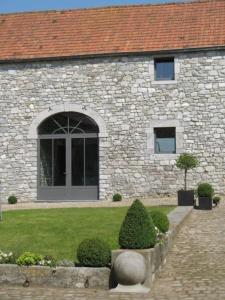 un edificio de piedra con una puerta y un patio en Ferme de la Porte Rouge, en Andenne