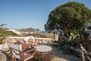 a patio with a table and chairs and a tree at Villa Marie-Iphigenie in Antiparos