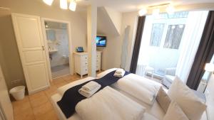 a bedroom with a white bed and a bathroom at Hotel Garni Auszeit in Boltenhagen