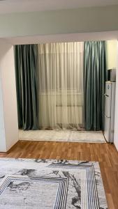 een woonkamer met groene gordijnen en een tapijt bij 2х комнатная квартира на Айтиева in Taraz