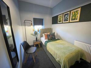 um pequeno quarto com uma cama e uma cadeira em Arena House - Sleeps 6 em Sheffield