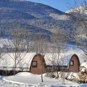 a building covered in snow with trees and mountains at Chez Fabien et Céline in Aunat