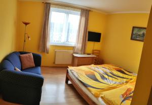 a bedroom with a bed and a chair and a window at Penzion Kozabar in Horní Luby