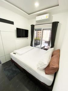 a bedroom with a white bed and a television at Moderne og delikat leilighet på stranden i Jomtien in Pattaya South