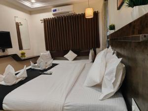 a hotel room with a large bed with white pillows at HOTEL SHIRDI INN in Shirdi