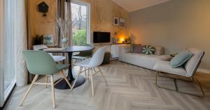 a living room with a table and chairs and a couch at Boslodge Bosmus - 4 personen tussen de bomen in Nunspeet