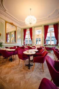 ein Restaurant mit Tischen, Stühlen und einem Kronleuchter in der Unterkunft Grand Hôtel de l'Europe in Morlaix