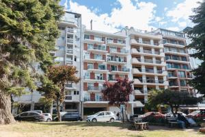 a large apartment building with cars parked in a parking lot at Departamento Vista Huapi in San Carlos de Bariloche