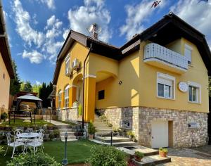 a yellow house with a patio and a table at Bükki Villa in Bükkszék