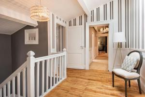 um corredor com uma escada com uma cadeira e um lustre em La Chambre "Rose" d'Hauterive em Villeneuve-sur-Lot