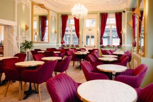 a restaurant with purple chairs and tables and windows at Grand Hôtel de l'Europe in Morlaix