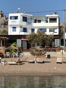 un edificio su una spiaggia con sedie e ombrelloni di Riva Del Mare a Archangelos
