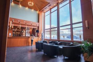 Eine Frau steht in einem Raum mit Stühlen und großen Fenstern. in der Unterkunft Hôtel La Plagne Le Terra Nova in La Plagne