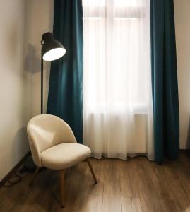 a chair and a lamp in a room with a window at HiRooms Brașov in Braşov