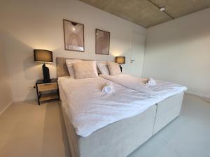 a large white bed in a bedroom with a night stand at SiOUX: stilvolles Designapartment am Bodensee in Lindau-Bodolz