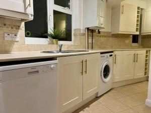 a kitchen with a sink and a washing machine at Treasure Chest Chessington in Ewell