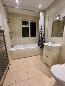 a bathroom with a tub and a toilet and a sink at Treasure Chest Chessington in Ewell