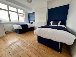 two beds in a bedroom with blue walls and wooden floors at Treasure Chest Chessington in Ewell