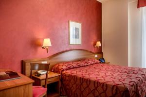 une chambre d'hôtel avec un lit rouge et une table dans l'établissement Hotel Tiffany, à Rimini