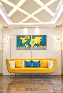 a yellow couch in a room with paintings on the wall at THE MARELLA SUITES in Bangalore