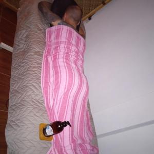 a man laying on a bed with a bottle of champagne at Affordable bedspacer good for 8 with breakfast in Clarin