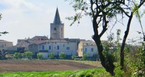 un antiguo edificio con una torre y una iglesia en Studio i Languedoc., en Nézignan-lʼÉvêque