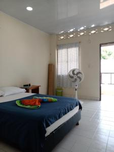 a bedroom with a bed with a blue blanket and a fan at Morada Ítaca - Arboletes in Arboletes