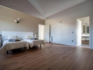 a white bedroom with two beds and wooden floors at La Atalaya in Las Navas del Marqués
