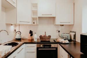 a kitchen with white cabinets and a black dishwasher at Higher Trewithen in Stithians
