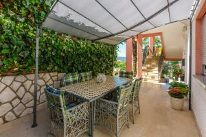 a table and chairs on a patio with a green wall at Apartmani Višnja in Crikvenica