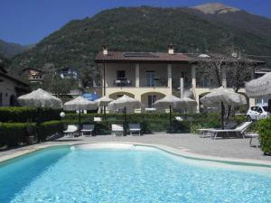 einen Pool mit Stühlen und Sonnenschirmen vor einem Haus in der Unterkunft Residence Letizia in Ossuccio