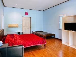 a bedroom with a red bed and a television at Baan Panmala Guesthouse - Ao Luek in Krabi town