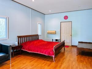 a bedroom with a red bed and a clock on the wall at Baan Panmala Guesthouse - Ao Luek in Krabi town