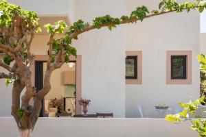 uma casa branca com uma árvore em primeiro plano em Mear Luxury Holiday Homes - Cretan Sunny Gems em Kountoura Selino