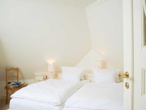 een wit bed met witte lakens en kussens bij Hummelhüs von Appartements & Mehr in Kampen