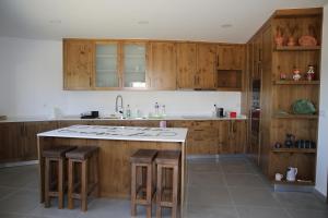 a kitchen with wooden cabinets and a island with bar stools at Casa da Teresinha in Bragança